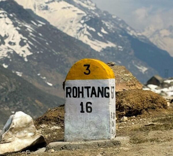 Rohtang Pass road milestone marked 16 with snow-covered Himalayan mountains in the background