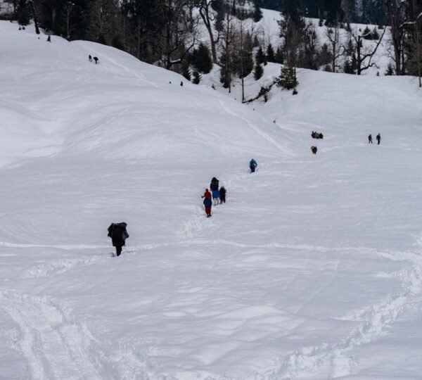 Visitors walking across the deep winter snow in Solang Valley near Manali